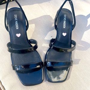 Black Steve Madden dress up shoes with a pink heart in the middle.